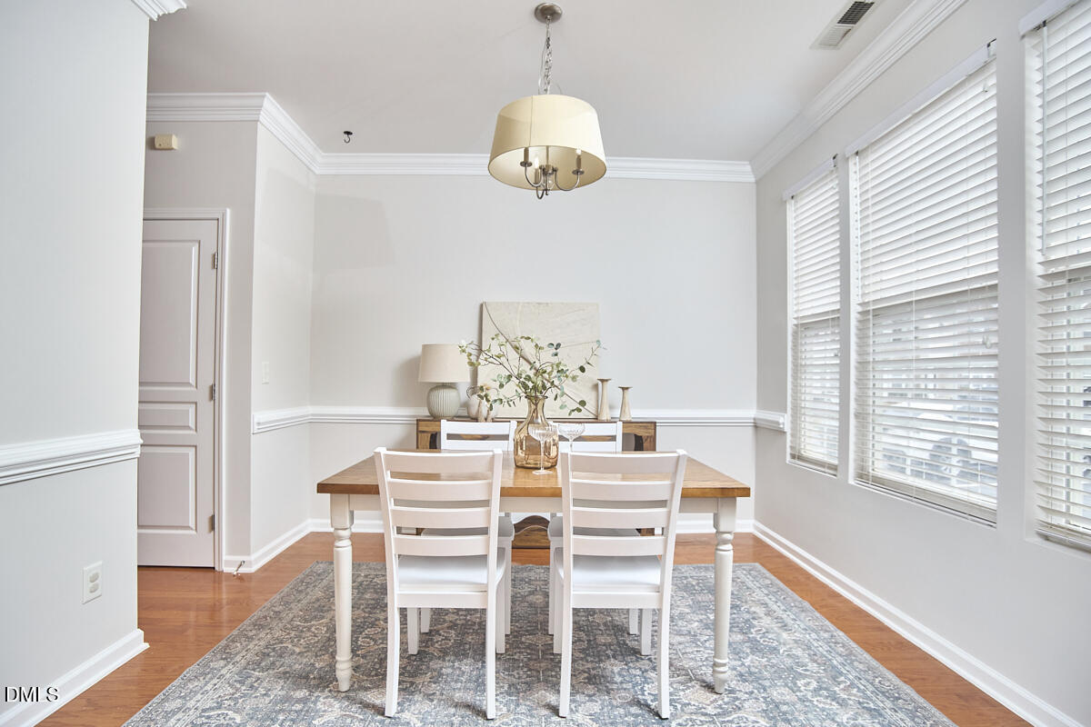 638 Cupola Drive Raleigh, NC 27603 - Photo 4 of 43 a dining room with wooden floor a chandelier a wooden table and chairs