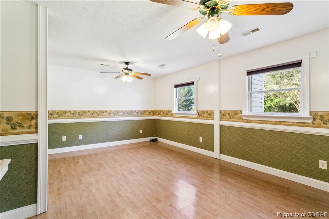 3255 Providence Road Hayes, VA 23072 - Photo 19 of 46 Bedroom 1 with ceiling fan, a wealth of natural light, and wood-type flooring. Originally 2 rooms. Replacing the wall in between could make a second bedroom.