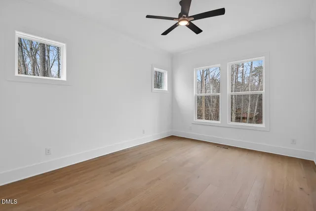 a view of an empty room with window and hardwood floor