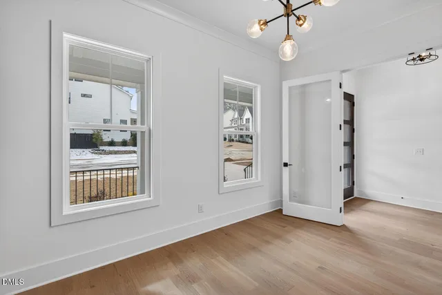 an empty room with wooden floor cabinet and windows