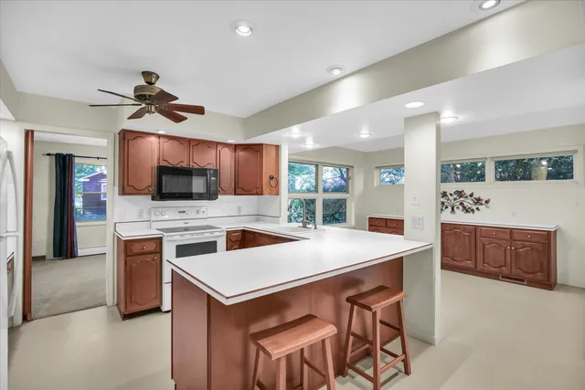 a kitchen with stainless steel appliances kitchen island granite countertop a refrigerator a stove and a sink with wooden floor