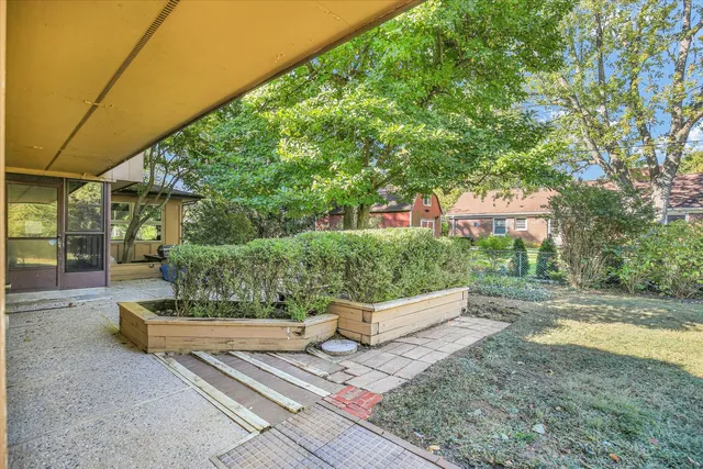 a view of backyard of house with large tree and wooden fence