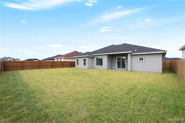 a view of a house with a yard and a large tree