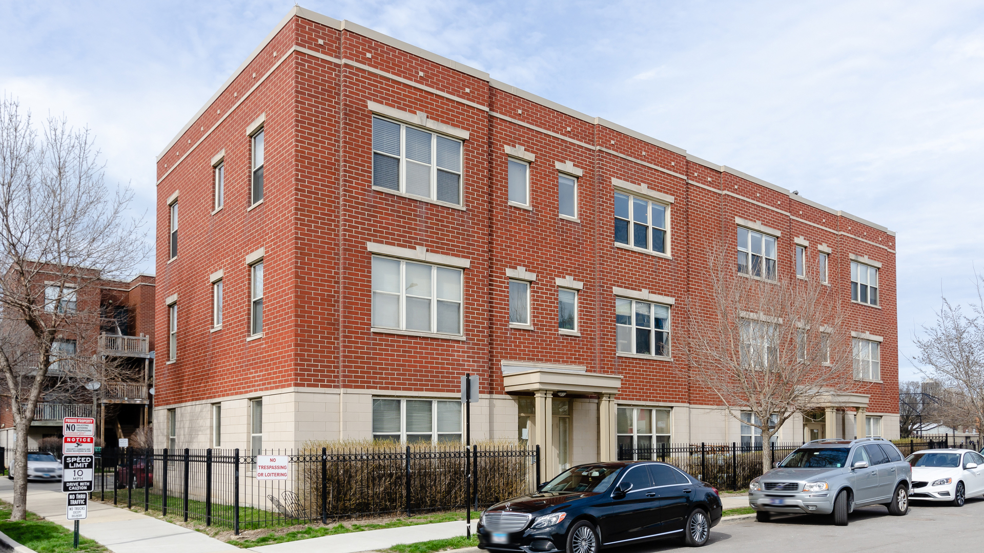 a front view of a building with lot of cars parked on city street