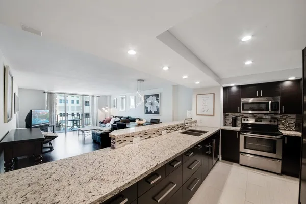 a kitchen with stainless steel appliances granite countertop a stove top oven a sink dishwasher and a refrigerator