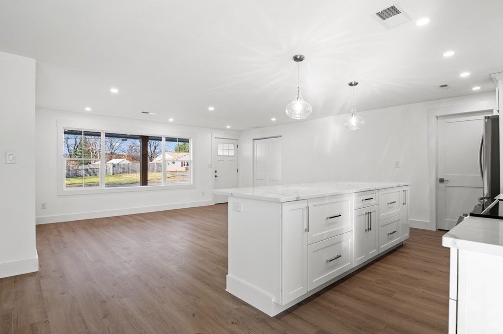 27 Trinity Street Danvers, MA 01923 - Photo 7 of 27 a large white kitchen with a large window a island wooden floor and stainless steel appliances