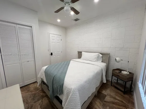 a bedroom with a bed a flat screen tv and a ceiling fan