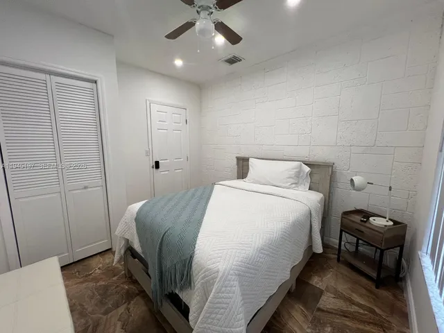a bedroom with a bed a flat screen tv and a ceiling fan
