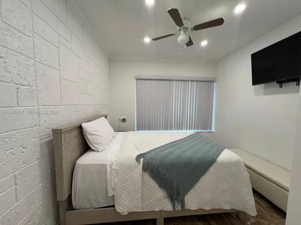 a bedroom with a bed tv and a window