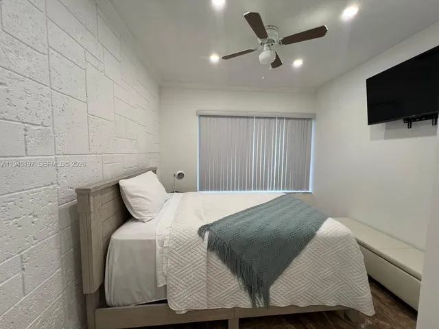 a bedroom with a bed tv and a window