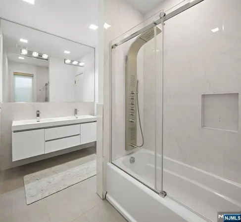 a bathroom with a double vanity sink a mirror and a bathtub