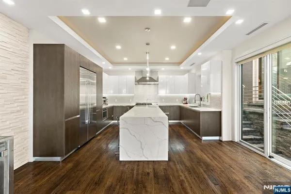 a large kitchen with stainless steel appliances kitchen island a large counter top and a refrigerator