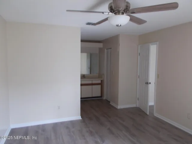 a view of a hallway with wooden floor and a ceiling fan