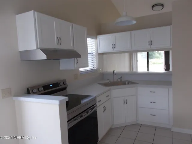 a kitchen with granite countertop white cabinets and a stove