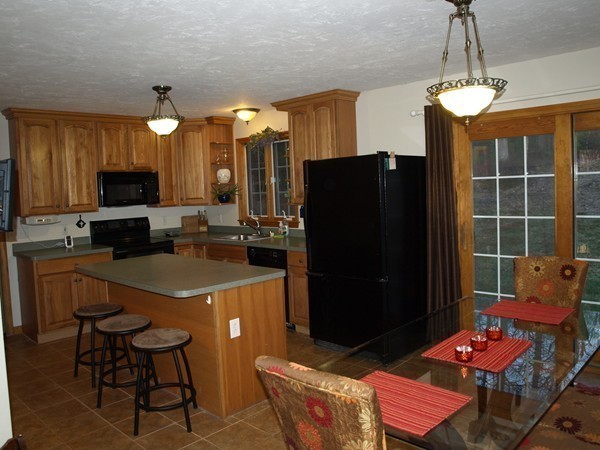 9 A Vinton Road Charlton, MA 01507 - Photo 6 of 23 a kitchen with stainless steel appliances granite countertop a refrigerator a sink a stove a dining table and chairs with wooden floor
