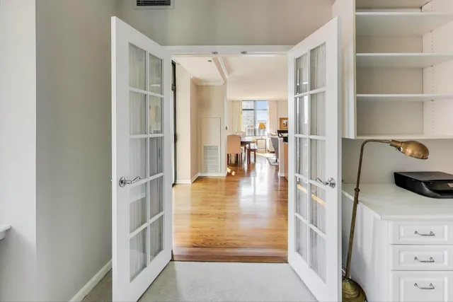 a hallway with white cabinets and chandelier