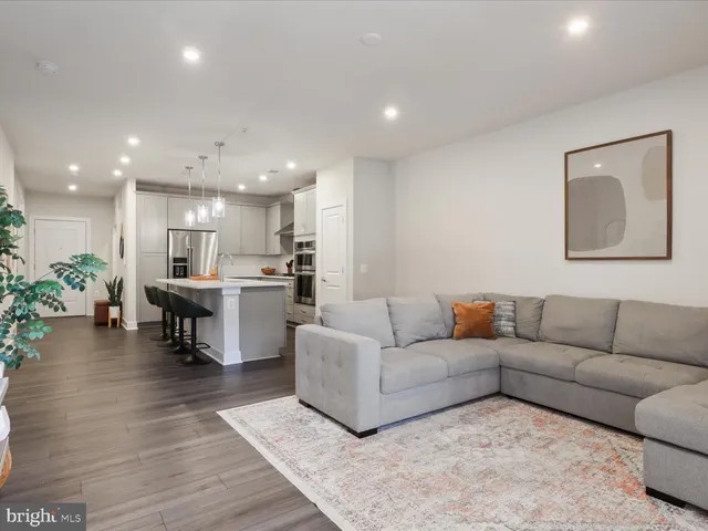 a living room with furniture and kitchen view with wooden floor