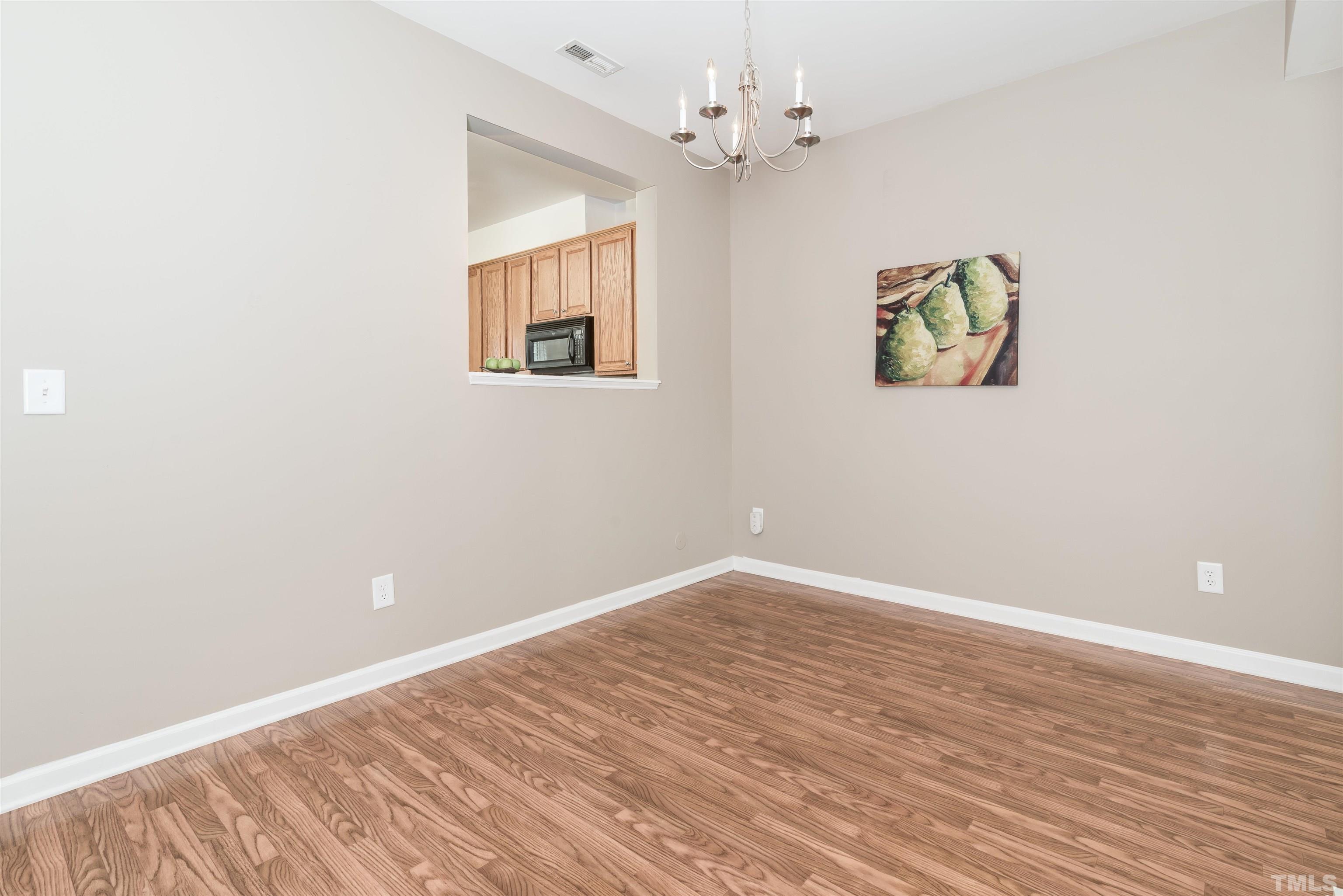 105 Graystar Road Apex, NC 27502 - Photo 13 of 35 an empty room with wooden floor chandelier fan and windows
