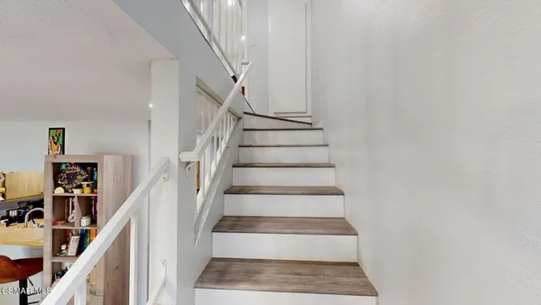 a view of staircase with white walls and a rug