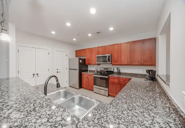 a large kitchen with stainless steel appliances granite countertop a stove a sink and a granite counter tops