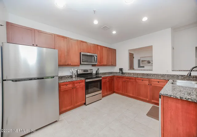 a kitchen with granite countertop a refrigerator stove top oven and sink