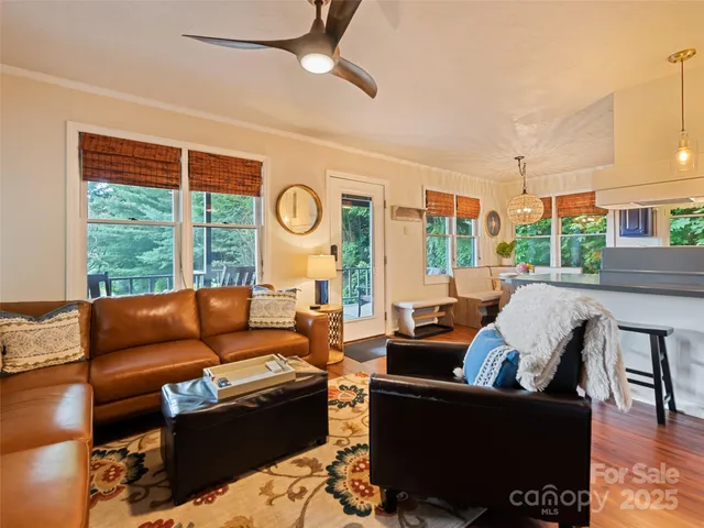 a living room with stainless steel appliances furniture a rug and a view of kitchen