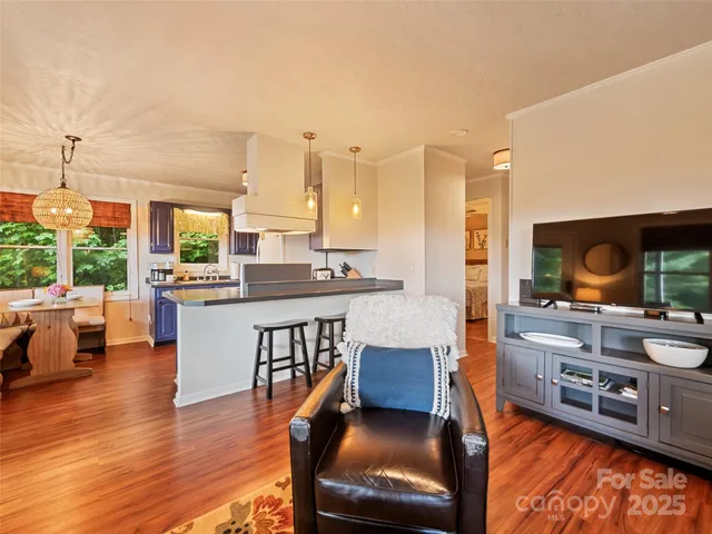 a kitchen with stainless steel appliances granite countertop table chairs and a view of living room