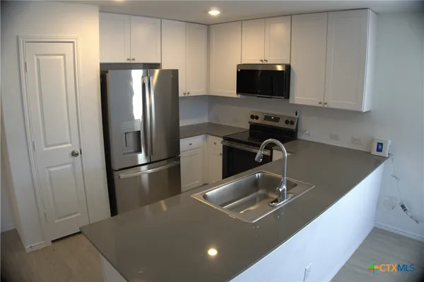 a kitchen with stainless steel appliances granite countertop a refrigerator a stove and a sink