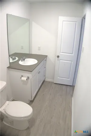a bathroom with a granite countertop toilet sink and mirror