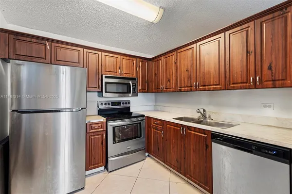 a kitchen with stainless steel appliances granite countertop a refrigerator stove a sink dishwasher and microwave