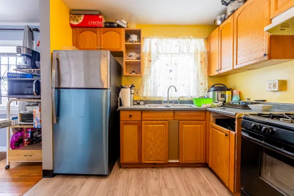 a kitchen with stainless steel appliances granite countertop a refrigerator a sink dishwasher and wooden cabinets with wooden floor
