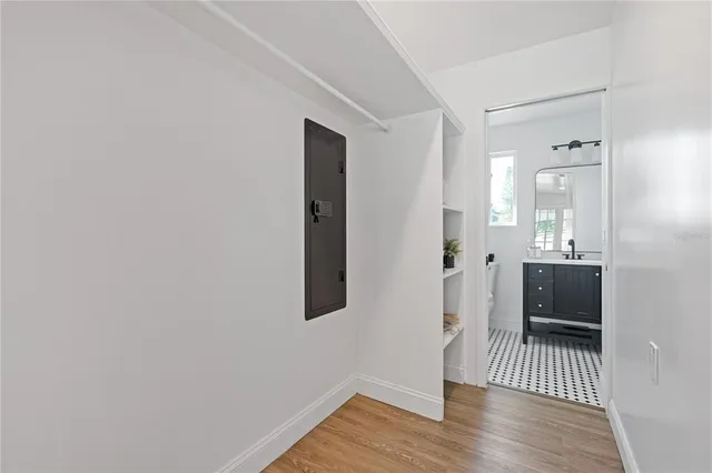 a view of a hallway with wooden floor and a bathroom