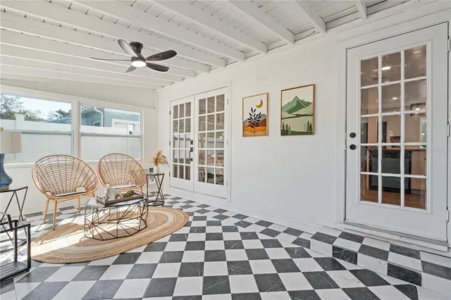 a living room with a black white checkered floor with a gaming machine and dining table