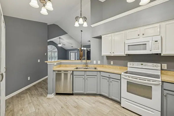 a kitchen with stainless steel appliances a stove a sink and white cabinets with wooden floor