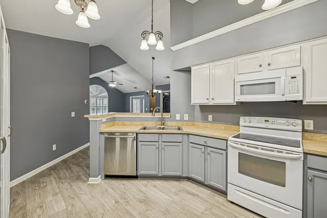 a kitchen with stainless steel appliances a stove a sink and white cabinets with wooden floor
