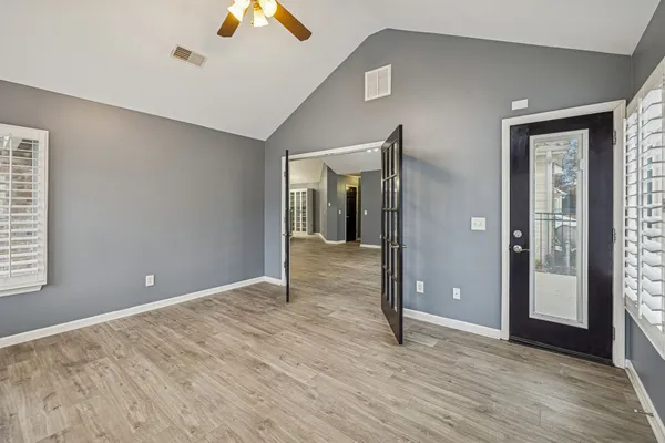 a view of an empty room with wooden floor and a window