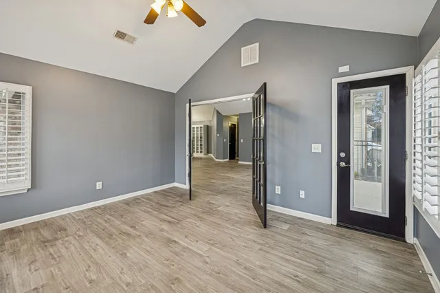 a view of an empty room with wooden floor and a window