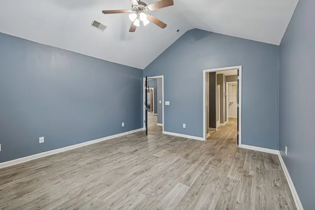 a view of an empty room with wooden floor and a chandelier