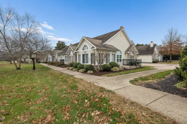 a view of a big house with a big yard and large tree and plants