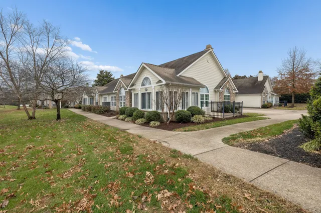 a view of a big house with a big yard and large tree and plants
