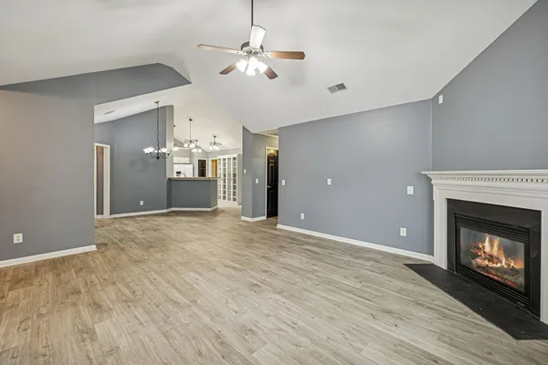 a view of a livingroom with a fireplace a chandelier fan and wooden floor