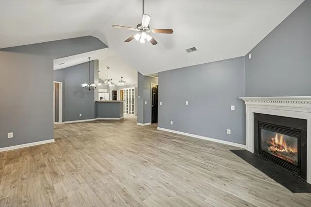 a view of a livingroom with a fireplace a chandelier fan and wooden floor
