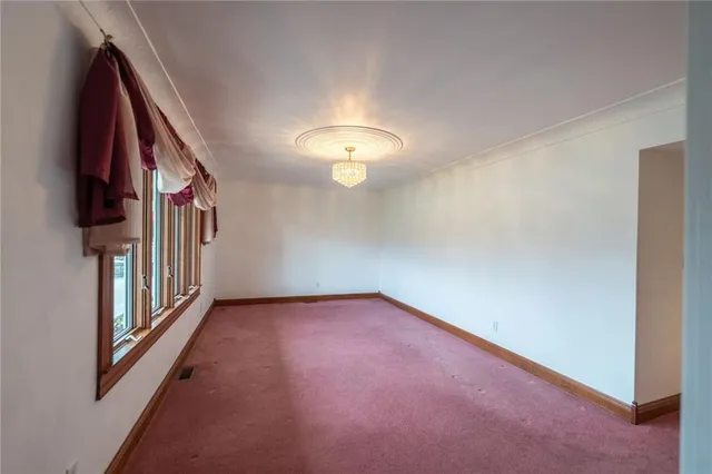 a view of an empty room with a chandelier fan and a window