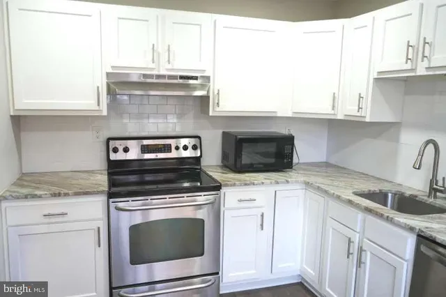 a kitchen with granite countertop a stove sink and cabinets