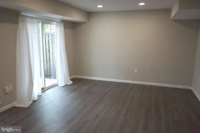 an empty room with wooden floor and windows with curtains view