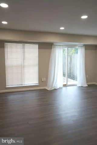 an empty room with wooden floor and windows with curtains