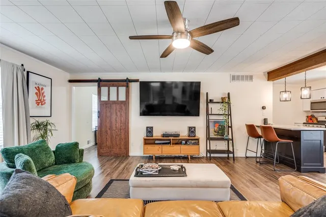 a living room with furniture a flat screen tv and kitchen view