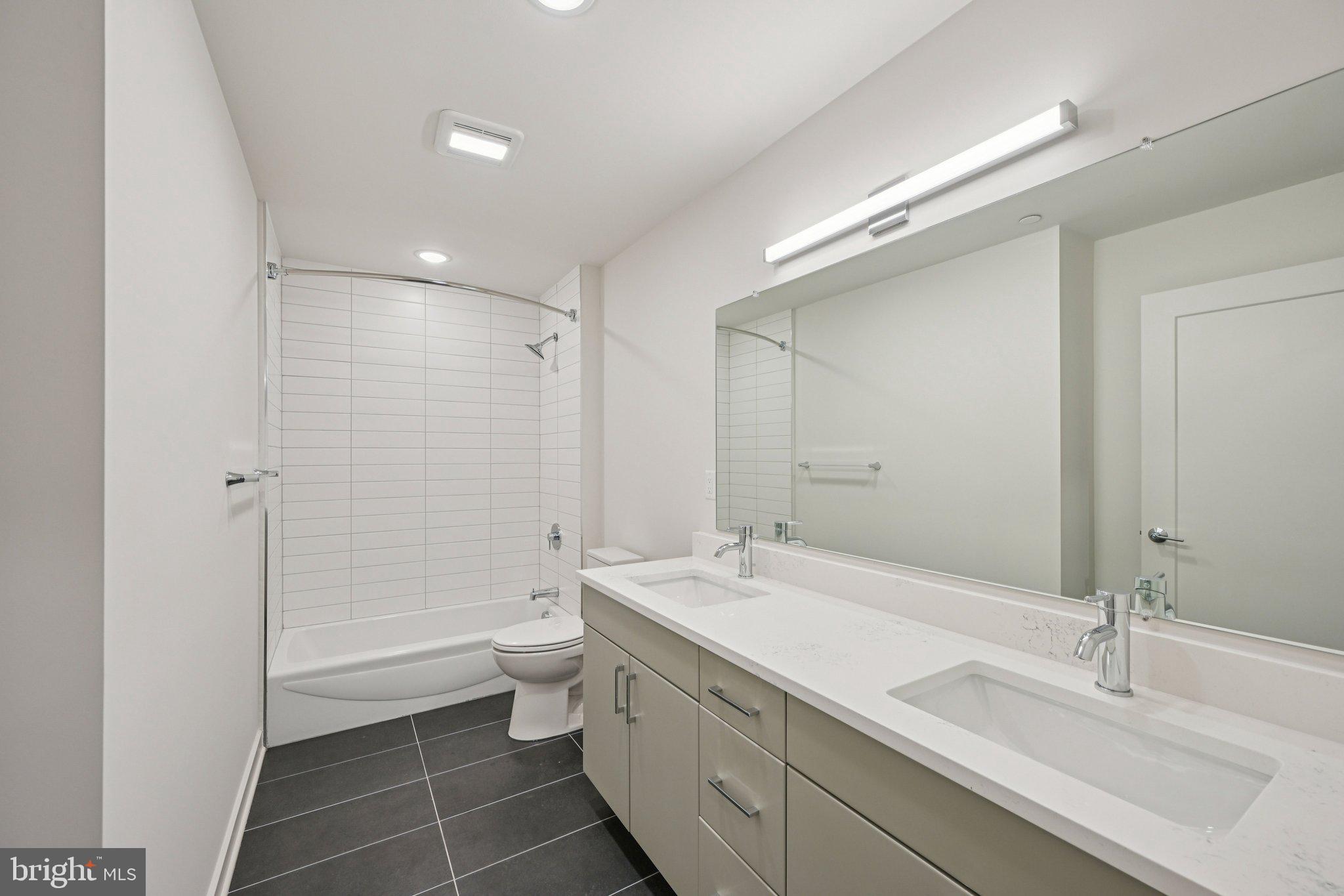 23 Rock Hill Road, Unit 210 Bala Cynwyd, PA 19004 - Photo 5 of 7 a bathroom with a double vanity sink toilet mirror and a bathtub