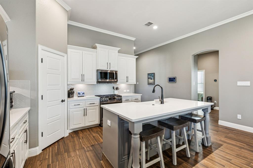 2925 Inn Kitchen Way McKinney, TX 75071 - Photo 8 of 40 a open kitchen with stainless steel appliances granite countertop a stove top oven a sink a refrigerator with white cabinets and wooden floor
