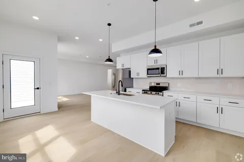 a kitchen with stainless steel appliances granite countertop a sink a window and white cabinets
